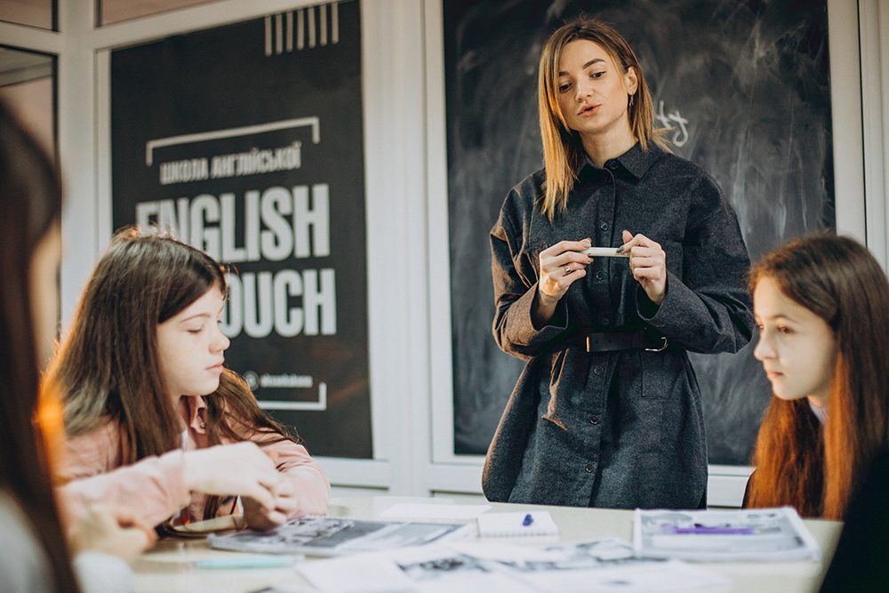 Professora em sala de aula explicando para seus alunos as diferenças de other e another.