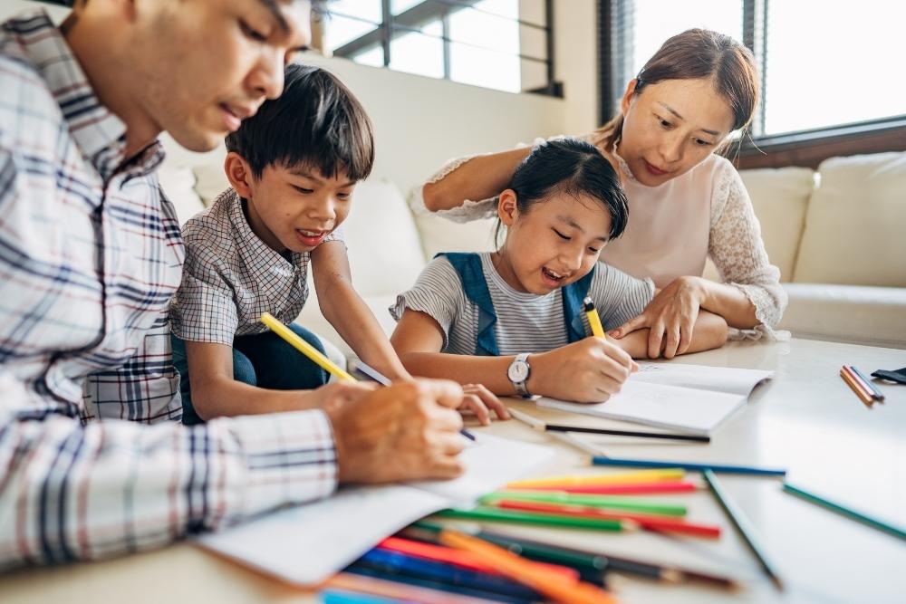 Família ajudando crianças com lição de casa na mesa.