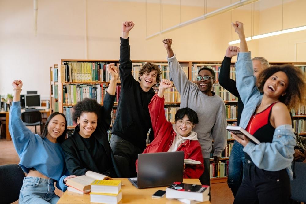 estudantes comemorando juntos em uma biblioteca.