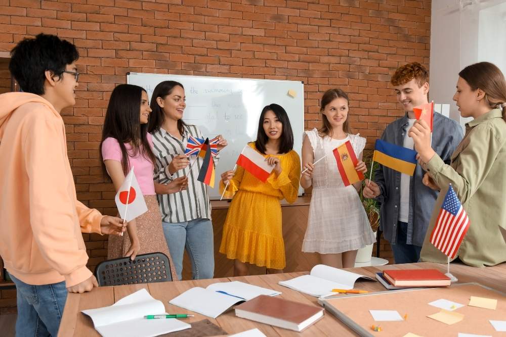 estudantes segurando bandeiras de diferentes países em aula de idiomas.