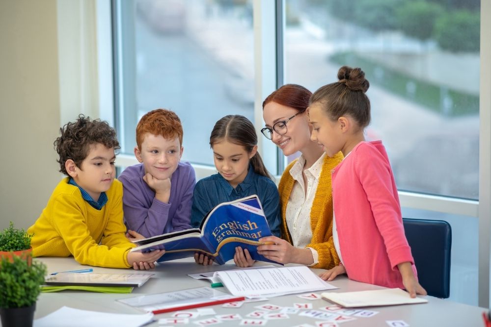 professora ensina gramática inglesa para crianças na sala de aula.