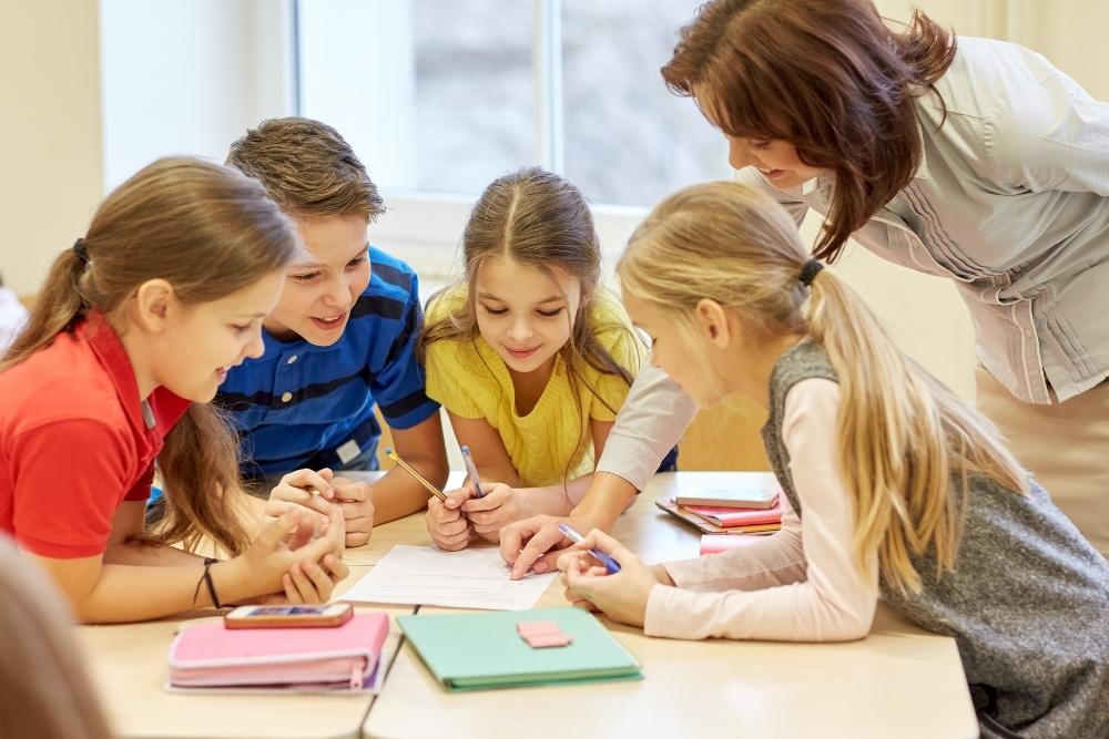 alunos em grupo realizando atividade colaborativa com apoio da professora.