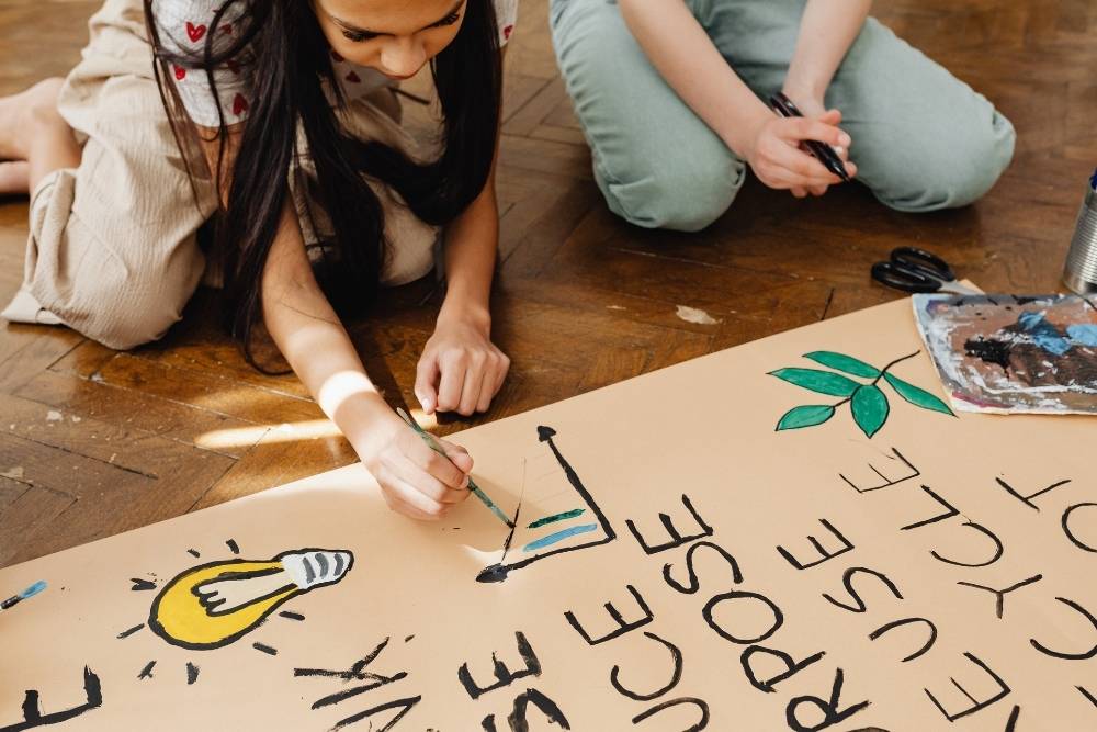 criança pintando cartaz educativo sobre reciclagem em atividade escolar.